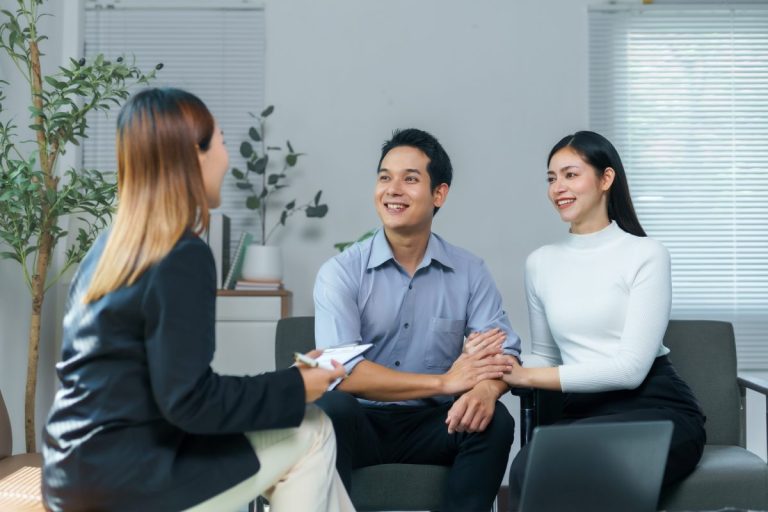 Cặp đôi nắm tay nhau, mỉm cười lắng nghe trong buổi tư vấn tâm lý